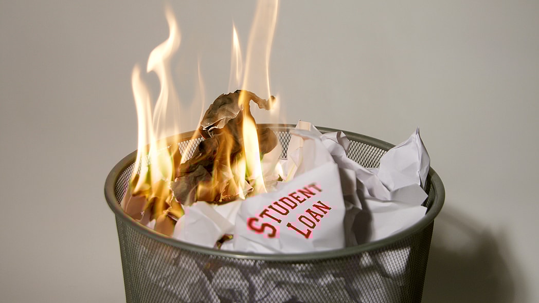 A paper reading "Student Loan" burning in a wastebasket