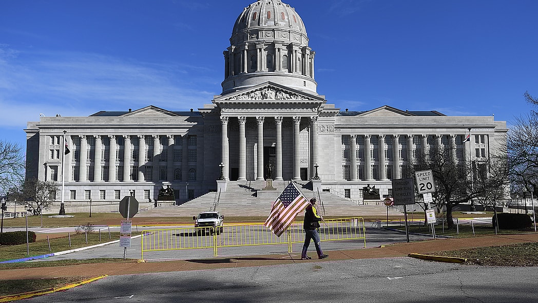 A man waves an American flag outside the Missouri State Capitol building