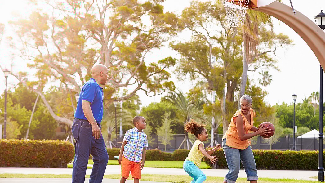 Grandparents And Grandchildren Playing Basketball Together Smiling