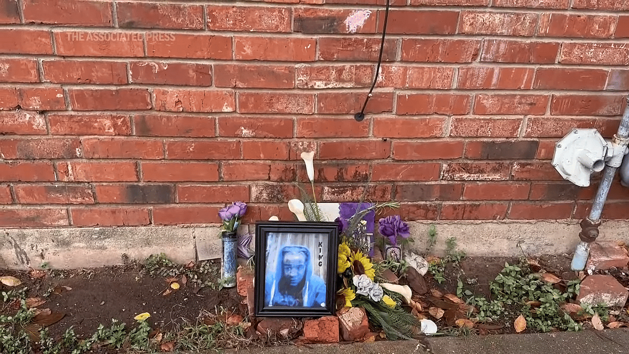 A memorial for a person by a brick wall with a photo and flowers