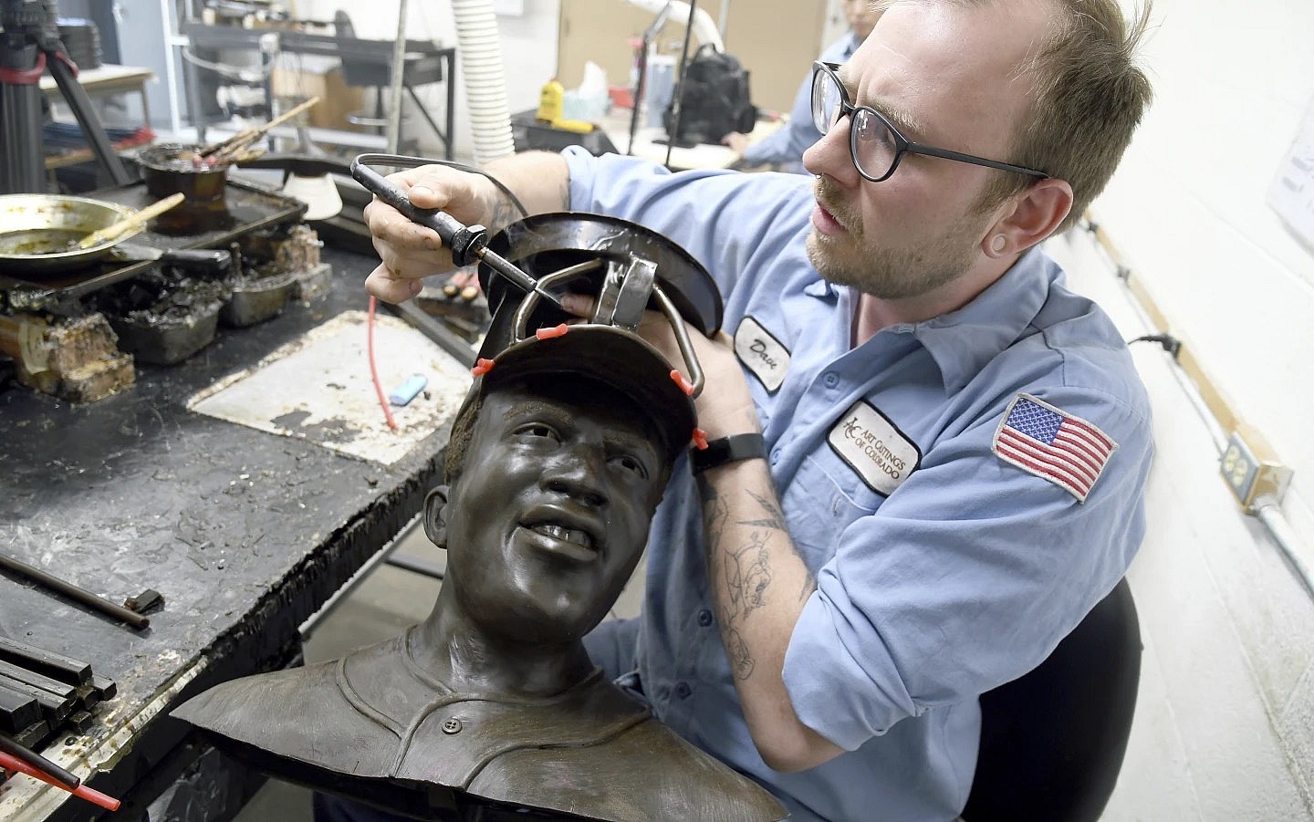 David Hobbs, an employee at Art Castings of Colorado, touches up a wax mold of Jackie Robinson’s head