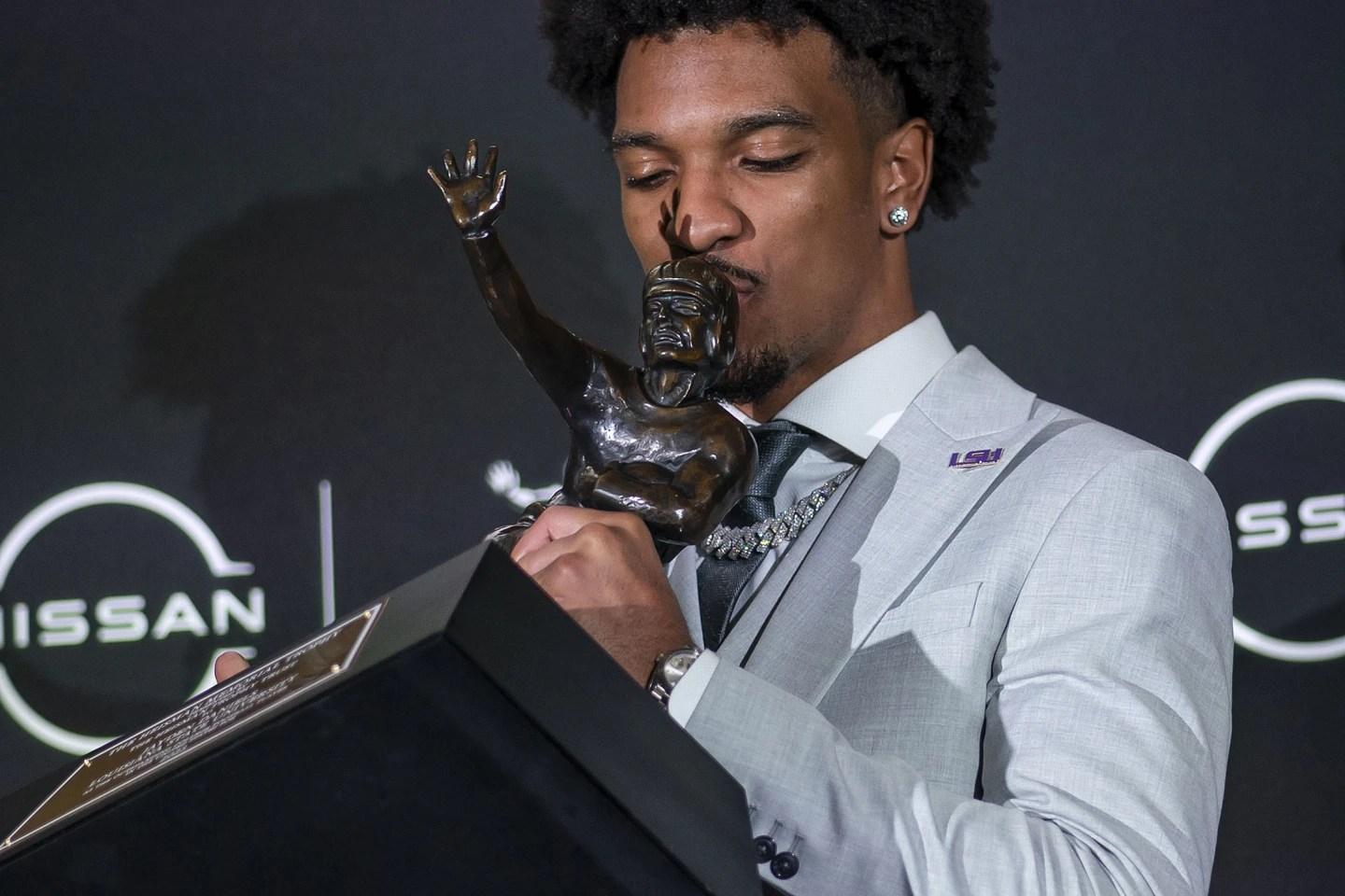 LSU quarterback Jayden Daniels kisses the Heisman Trophy