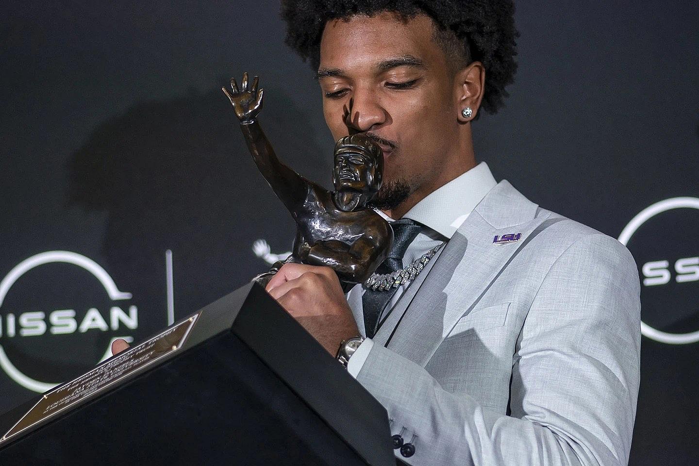 LSU quarterback Jayden Daniels kisses the Heisman Trophy