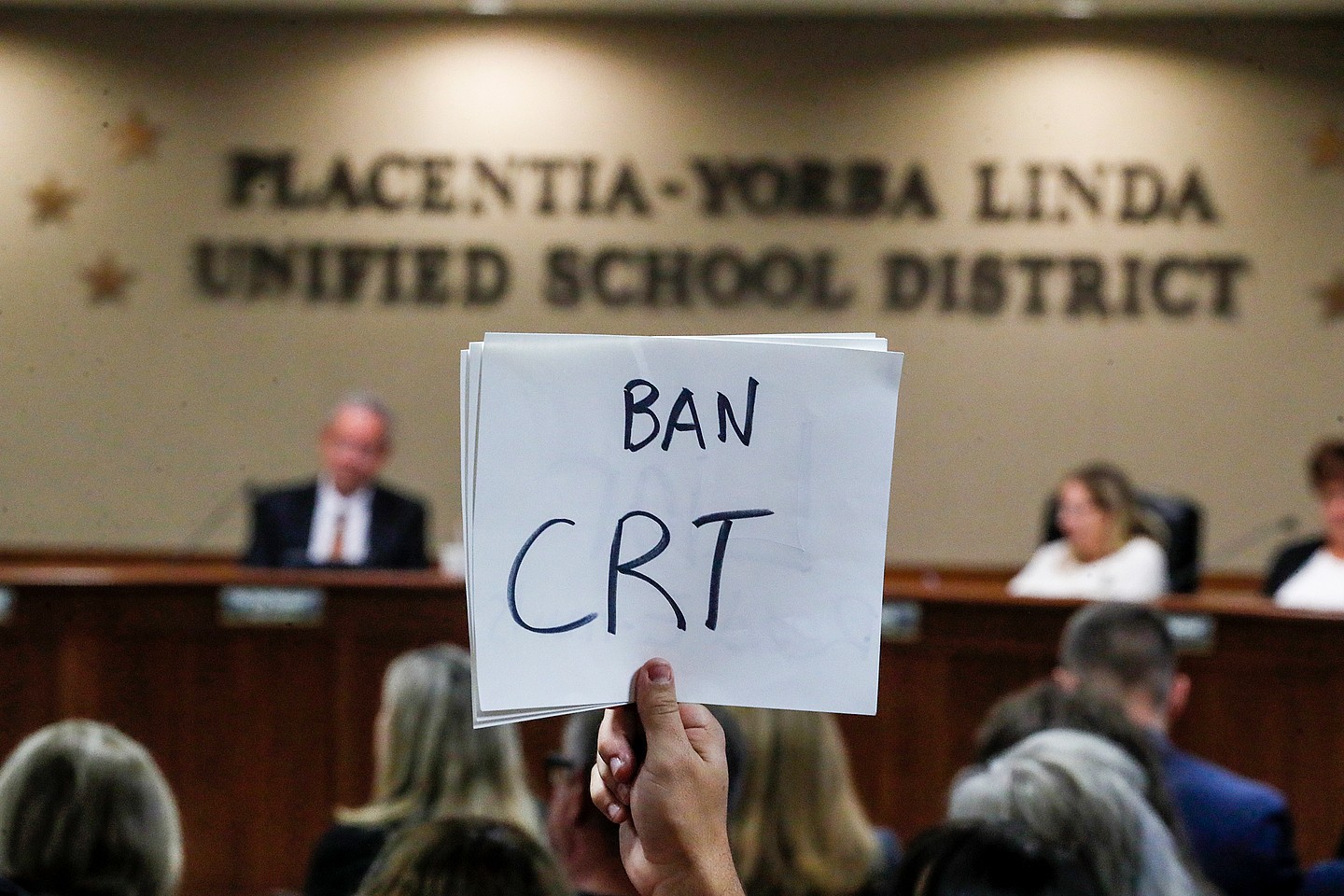 A hand holding a sign reading "Ban CRT"
