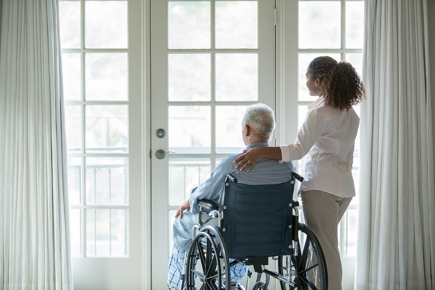 A woman stands beside a man in a wheelchair