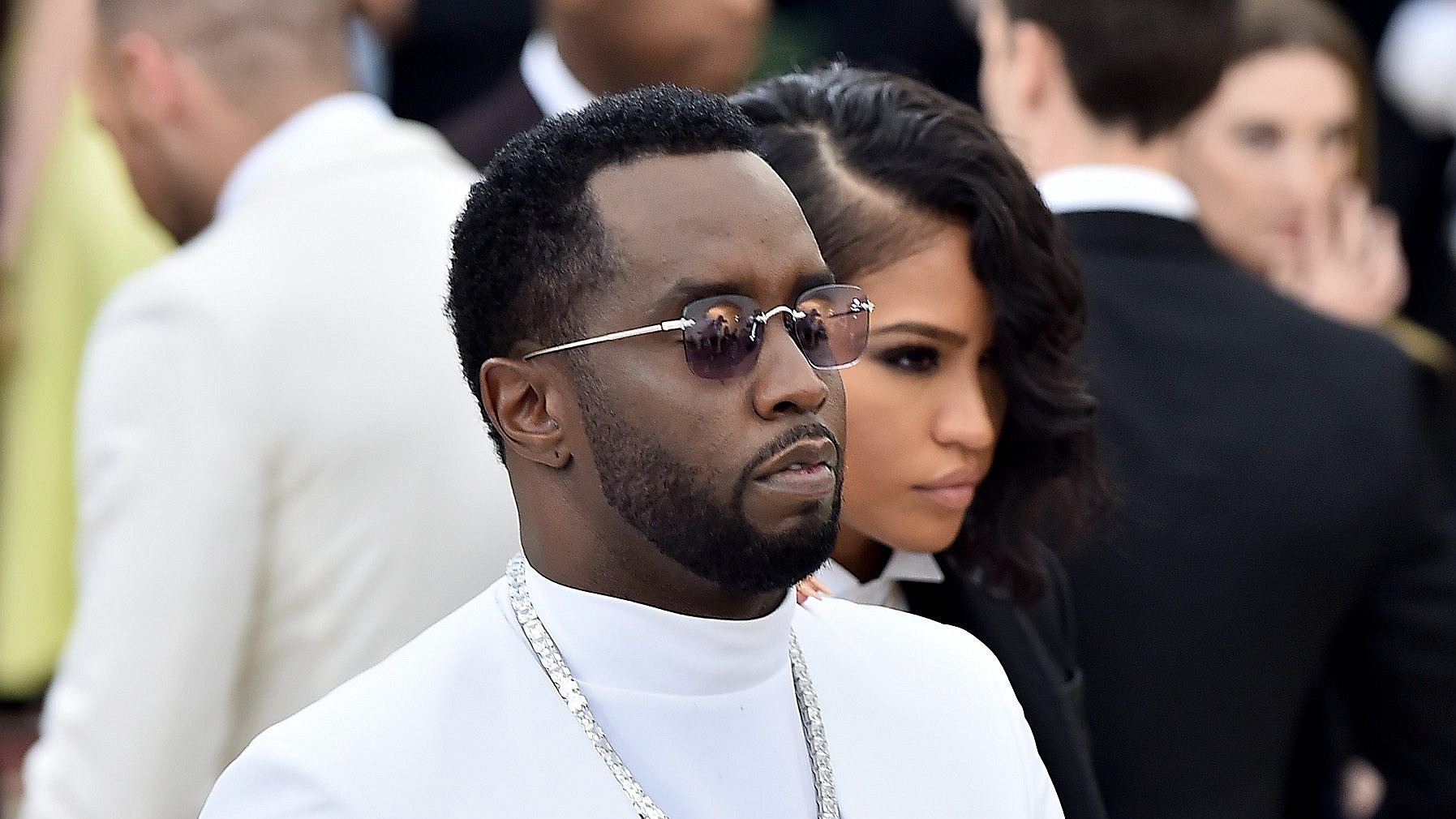 Record producer and rapper Sean "Diddy" Combs stands wearing a white suit, silver chain and sunglasses