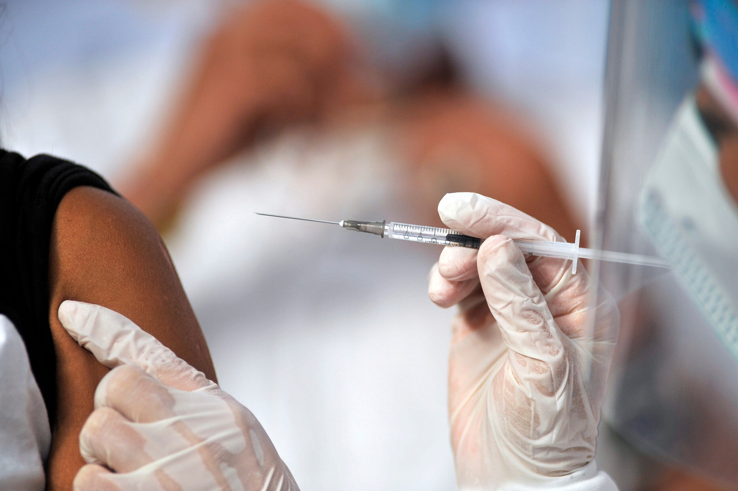A health worker gives a man a shot of the Jenssen COVID-19 vaccine from the Johnson & Johnson - theGrio.com
