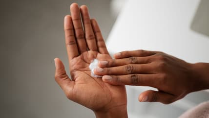A hand rubbing in lotion on another hand