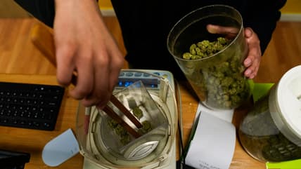 Budtender Rey Cruz weighs cannabis for a customer