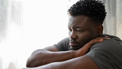 Young and depressed adult at home, Black men mental health