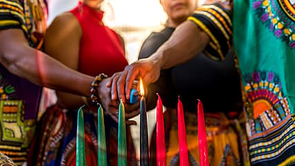 A family lighting the black Kwanzaa candle