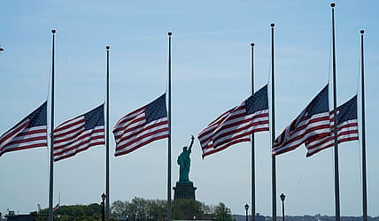 U.S. flags, across New York Bay from the Statue of Liberty, fly at half-staff