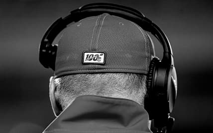 The back of a man's head wearing a baseball cap and headset