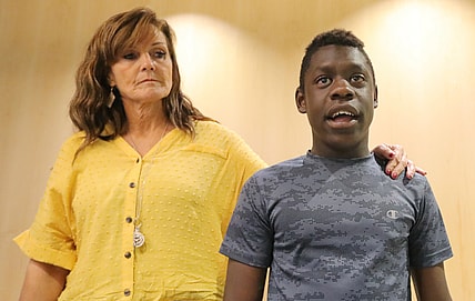 In this June 7, 2019 file photo, Jerri Hrubes stands next to her son DJ during a news conference Friday, June 7, 2019, in Salt Lake City. About 100 protesters gathered outside a police agency, Friday, June 14, to demand an officer who pulled his gun on 10-year-old Hrubes last week be fired. The officer's actions drew criticism after Jerri Hrubes said the white police officer pulled his gun on her son, DJ, who is black, while he was playing on his grandmother's front lawn on June 6. (AP Photo/Rick Bowmer)