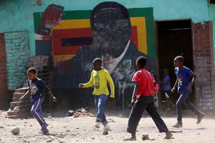 Children play soccer next to a defaced portrait of Former Zimbabwean President Robert Mugabe in Harare, Friday, Sept, 6 2019.Former Zimbabwean President Robert Mugabe has died, his successor president Emmerson Mnangagwa has confirmed. Mugabe was 95 and died at a Singapore Hospital.(AP Photo/Tsvangirayi Mukwazhi) thegrio.com