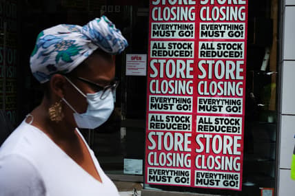 Black woman in front of "Store Closing" sign on business, theGrio.com