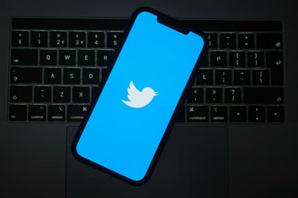 The Twitter logo on a cell phone screen over a keyboard