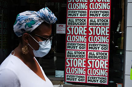 Black woman in front of "Store Closing" sign on business, theGrio.com