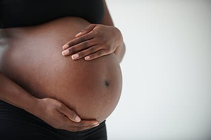 pregnant Black woman holding belly theGrio.com