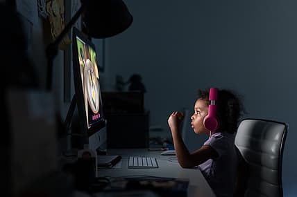 A child wearing headphones looks at a computer screen