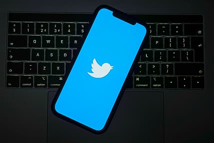 The Twitter logo on a cell phone screen over a keyboard