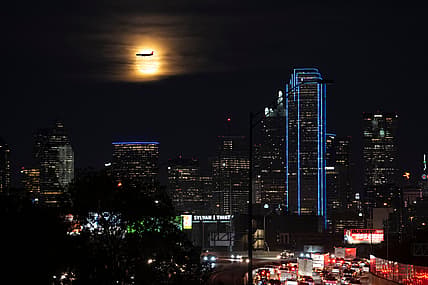 A Southwest Airlines plane makes its final approach at Dallas Love Field Airport near a the full moon