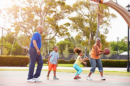 Grandparents And Grandchildren Playing Basketball Together Smiling