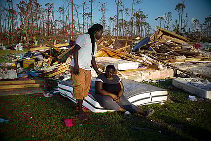 Synobia Reckley pauses on a wet mattress as her husband Dexter Edwards consoles her amid the remains of their home destroyed by Hurricane Dorian in Rocky Creek East End, Grand Bahama, Bahamas, Sunday, Sept. 8, 2019. The couple married two days after Hurricane Mathew hit in 2016 but did not do serious damage. (AP Photo/Ramon Espinosa) thegrio.com