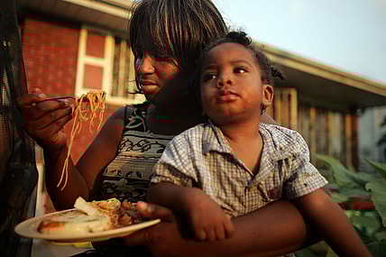 Mom feeding child food theGrio.com