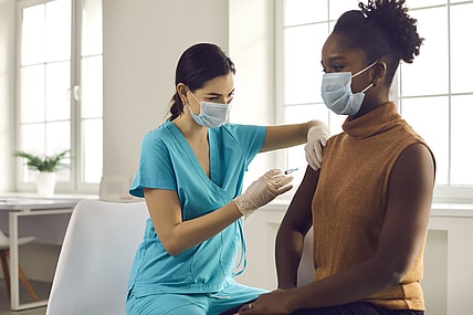 Black people health care system -- woman getting modern flu or Covid-19 vaccine at doctor's office