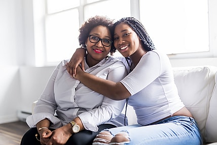 A affectionate mother and daughter sitting on a sofa