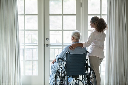 A woman stands beside a man in a wheelchair