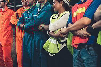 A group of workers with arms crossed holding hands