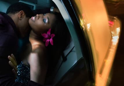 A man kisses a woman on the neck in a car