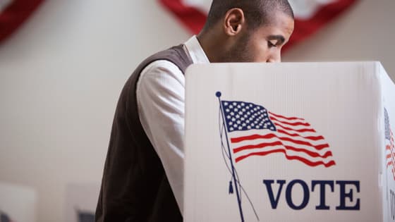A Black male voter inside a voting booth