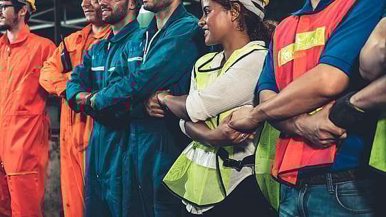A group of workers with arms crossed holding hands