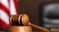 Judge Wooden gavel on the table of judge with american flag and black chair
