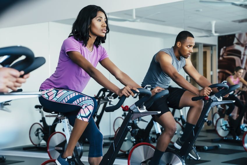 People cycling in a spin class at a gym thegrio