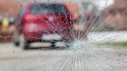 Broken windshield with red car in background