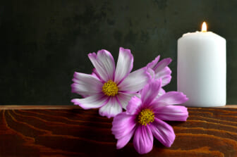 White burning candle and flowers thegrio.com
