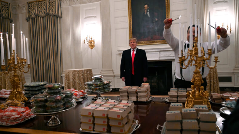 n this Jan. 14, 2019 photo, President Donald Trump talks to the media about the table full of fast food in the State Dining Room of the White House in Washington, for the reception for the Clemson Tigers. The partial government shutdown is hitting home for President Trump in a very personal way. He lives in government-run housing, after all. Just 21 of the roughly 80 people who help care for the White House _ from butlers to electricians to chefs _ are reporting to work. The rest have been furloughed. (AP Photo/Susan Walsh) thegrio.com