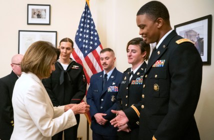 In this Tuesday, Feb. 5, 2019 photo released by the her office, Speaker of the House Nancy Pelosi, D-Calif., left, gives challenge coins to U.S. Army Maj. Ian Brown, right, and other military service members to thank them for their service, in her office at the Capitol following the State of the Union address in Washington. Brown, 38, is a two-time Bronze Star recipient who transitioned from female to male while advising the Army's deputy chief of staff in operations and planning. (Julio Obscura/Office of the Speaker of the House Nancy Pelosi via AP)