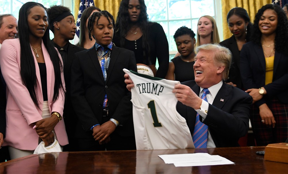 President Donald Trump holds up a jersey that was presented to him as he welcomed members of the Baylor women's basketball team, who are the 2019 NCAA Division I Women's Basketball National Champions, to the Oval Office of the White House in Washington, Monday, April 29, 2019. (AP Photo/Susan Walsh) thegrio.com