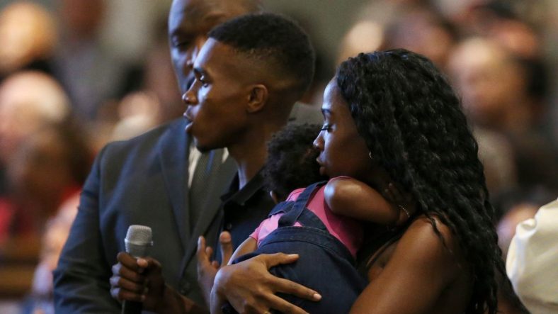 Dravon Ames, holding microphone, speaks to Phoenix Police Chief Jeri Williams and Phoenix Mayor Kate Gallego, as his fiancee, Iesha Harper, right, holds 1-year-old daughter London, at a community meeting, Tuesday, June 18, 2019, in Phoenix. The community meeting stems from reaction to a videotaped encounter that surfaced recently of Ames and his pregnant fiancee, Harper, having had guns aimed at them by Phoenix police during a response to a shoplifting report, as well as the issue of recent police-involved shootings in the community. (AP Photo/Ross D. Franklin)