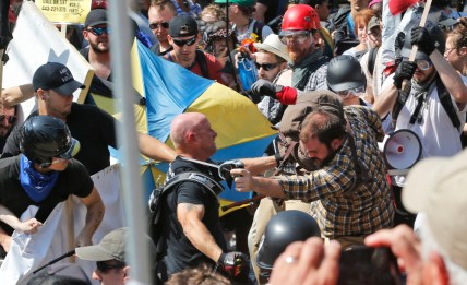 In this Aug. 12, 2017 file photo, white nationalist demonstrators clash with counter demonstrators at the entrance to Lee Park in Charlottesville, Va. Three alleged members of a white supremacist group accused of inciting violence at California political rallies were cleared of federal charges after a judge found their actions amounted to constitutionally protected free speech. The judge in Los Angeles on Monday, June 3, 2019 threw out charges of conspiracy to commit rioting and travel or use of commerce with intent to riot against the men. Prosecutors were disappointed with the ruling and reviewing grounds for appeal. (AP Photo/Steve Helber, File)