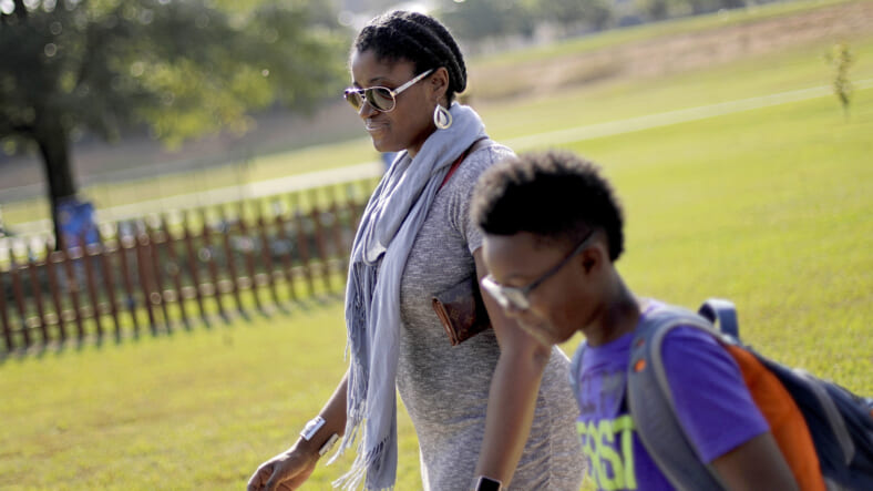 In this Oct. 11, 2017 file photo, Corrie Davis, left, picks up her son Turner from Big Shanty Elementary School in Kennesaw, Ga. The previous month, the school invited fifth-graders to dress up as characters from the Civil War. Davis says a white student dressed as a plantation owner approached her son and said "You are my slave." She requested that the school to stop the annual Civil War dress-up day. Recently, an investigation by New York Attorney General Letitia James found in May that a mock "slave auction" that singled out black students at the private Chapel School in Westchester County had a profoundly negative effect on all involved students. (AP Photo/David Goldman, File)