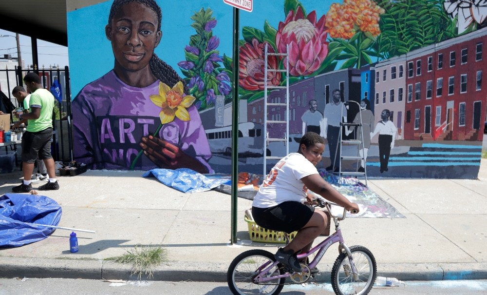 A boy rides his bicycle after volunteering to paint a mural outside the New Song Community Church in the Sandtown section of Baltimore. In the latest rhetorical shot at lawmakers of color, President Donald Trump over the weekend vilified Cummings' majority-black Baltimore district as a "disgusting, rat and rodent infested mess" where "no human being would want to live." (AP Photo/Julio Cortez)