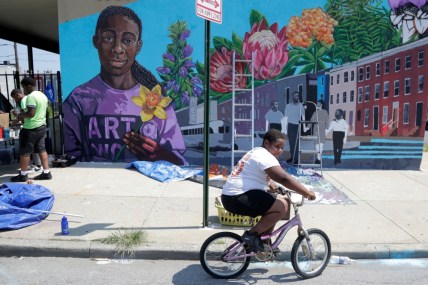 A boy rides his bicycle after volunteering to paint a mural outside the New Song Community Church in the Sandtown section of Baltimore. In the latest rhetorical shot at lawmakers of color, President Donald Trump over the weekend vilified Cummings' majority-black Baltimore district as a "disgusting, rat and rodent infested mess" where "no human being would want to live." (AP Photo/Julio Cortez)