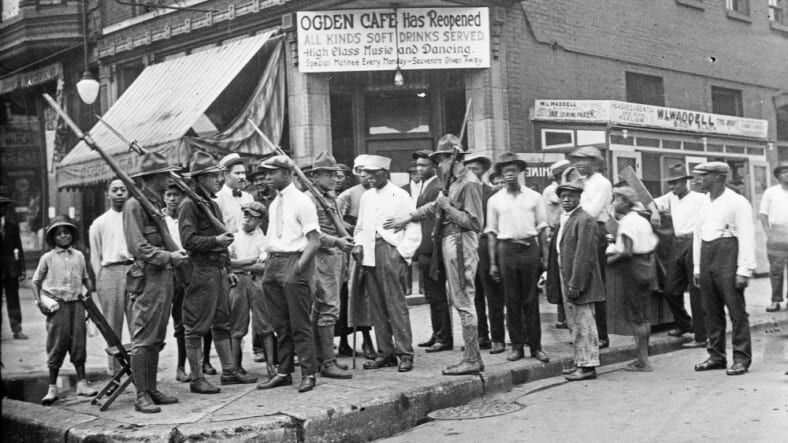 Crowd of men and armed National Guard in front of the Ogden Cafe during the race riots in Chicago, Illinois, 1919.