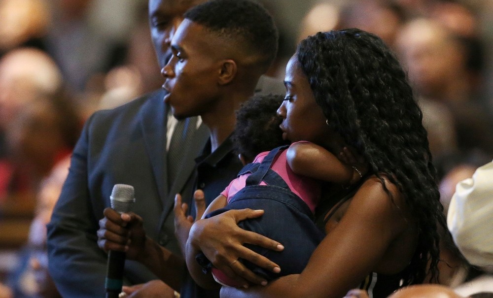 In this June 18, 2019 file photo Dravon Ames, holding microphone, speaks to Phoenix Police Chief Jeri Williams and Phoenix Mayor Kate Gallego, as his fiancee, Iesha Harper, right, holds 1-year-old daughter London, at a community meeting in Phoenix. Still stinging from national outrage sparked this summer by a videotaped encounter of officers pointing guns and cursing at the family, community members are holding low-key meetings aimed at helping Phoenix officials figure out how citizens could help oversee the city's officers. (AP Photo/Ross D. Franklin, File) thegrio.com